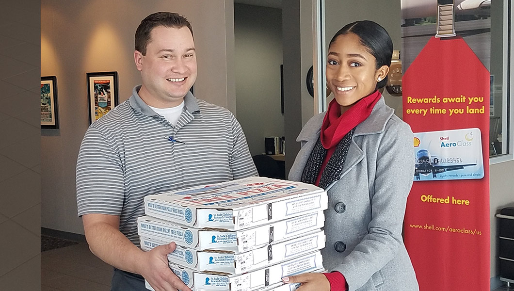 Mike Melton, Manager of Operations at the Atlanta Regional Airport Falcon Field, accepts a pizza lunch for their staff from Aventure Aviation's Chelsea Sneed.
