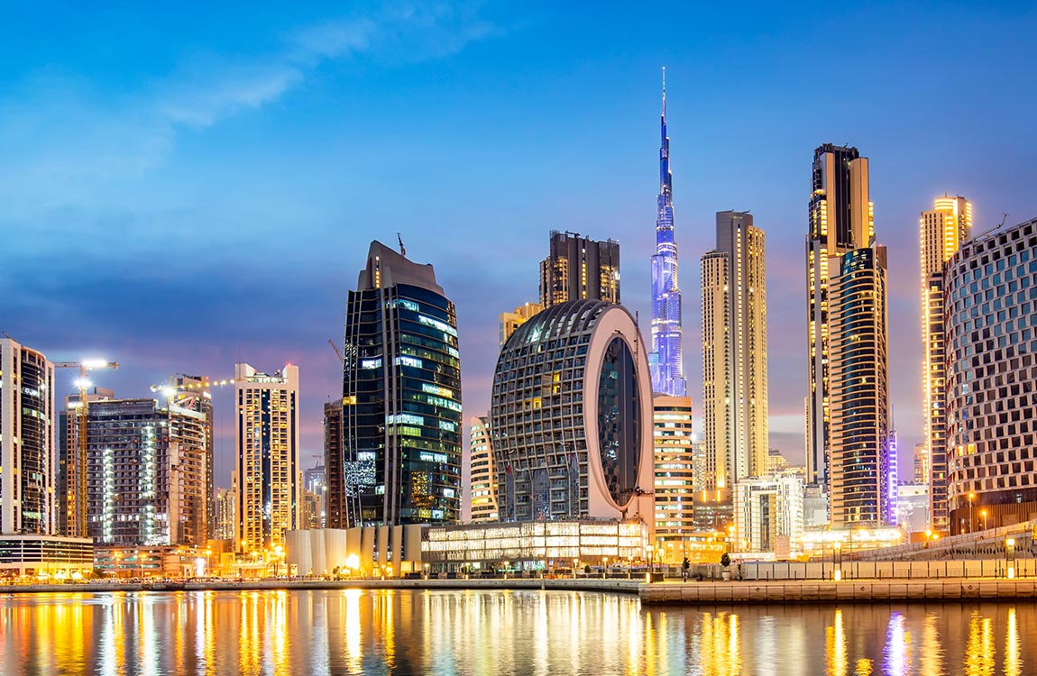 Dubai skyline at dusk, with skyscrapers reflecting in the sea below 