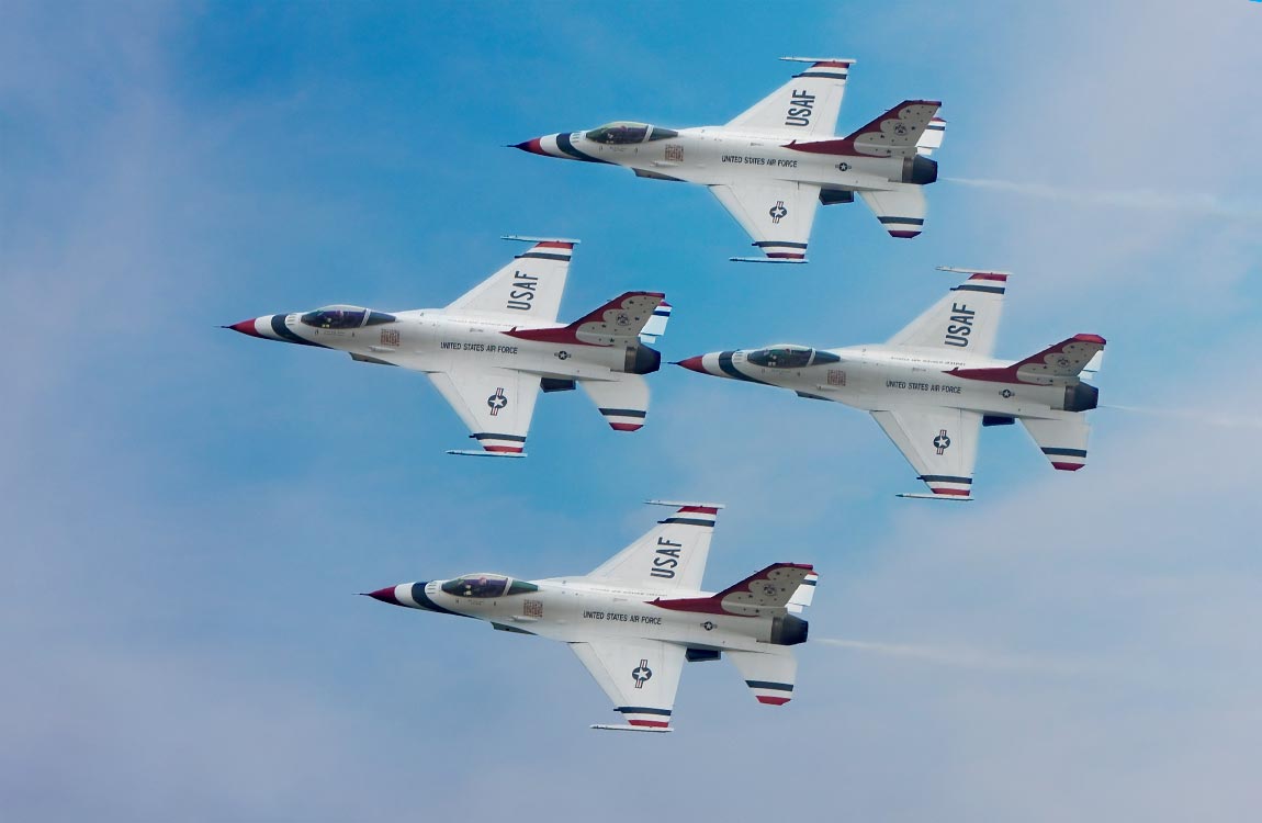 Four U.S. Air Force jet fighters in close formation streak through the sky 