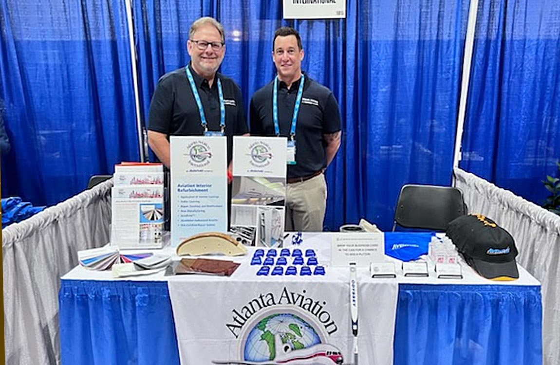 Two men standing behind a table at a trade show booth 